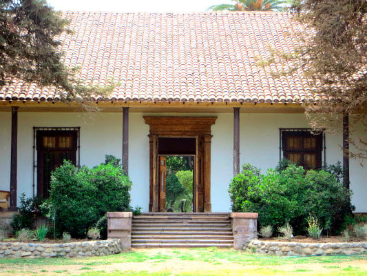 Casona blanca con árboles y arbustos