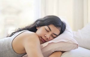 Una mujer apoyada en una almohada en su cama durmiendo