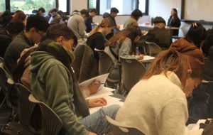 "Estudiantes rindiendo 1° Ensayo PAES UC 2026 de Competencia Lectora en Campus San Joaquín UC".