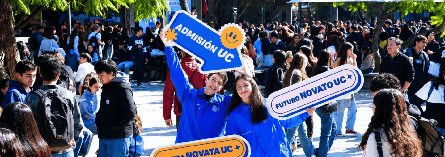 dos estudiantes felices sosteniendo letrero que dice admisión uc en patio de facultad universitaria